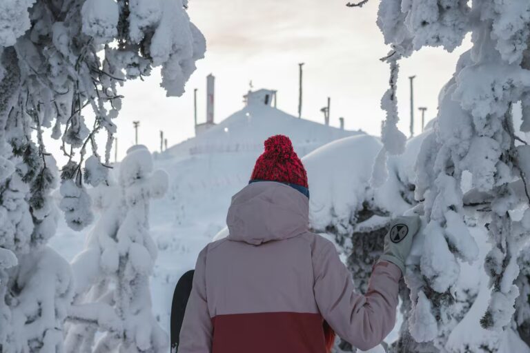 girl with snowboard watching peak of Rukatunturi