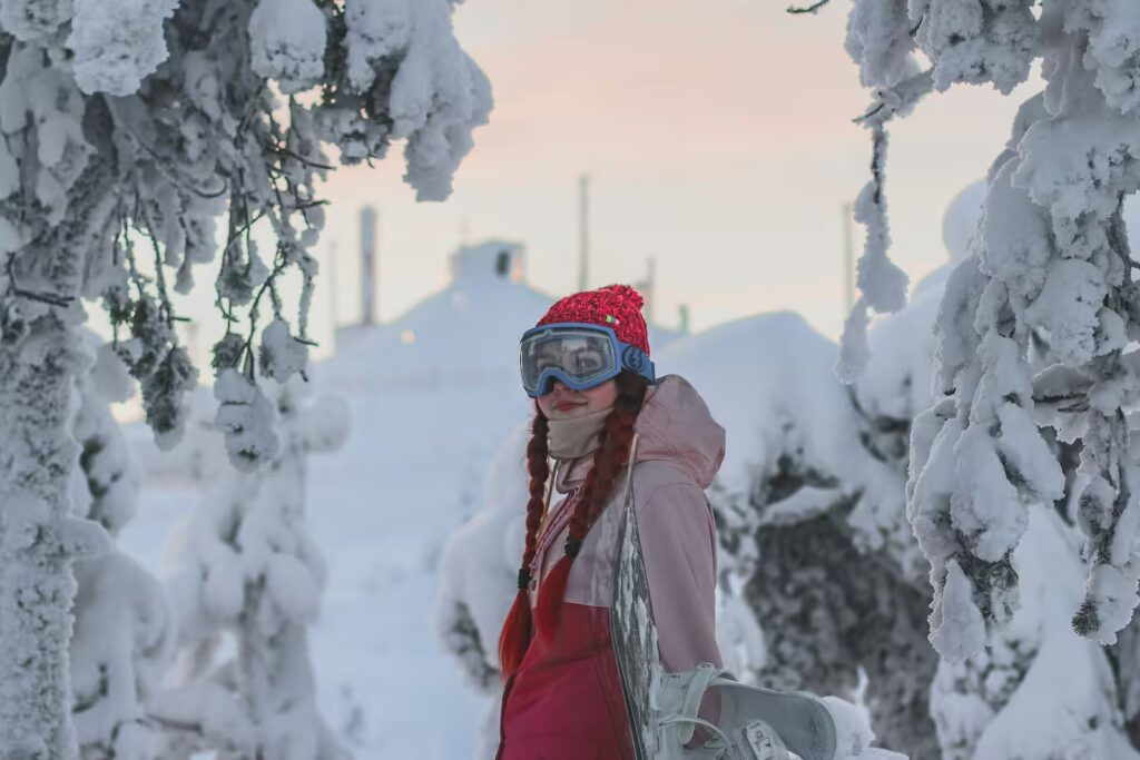 Girl with snowboard standing in front of Ruka