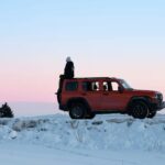 Man sitting on the trunk of SUV on winter day